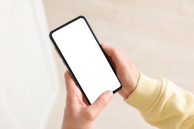 Photo of Woman using modern smartphone at home, closeup