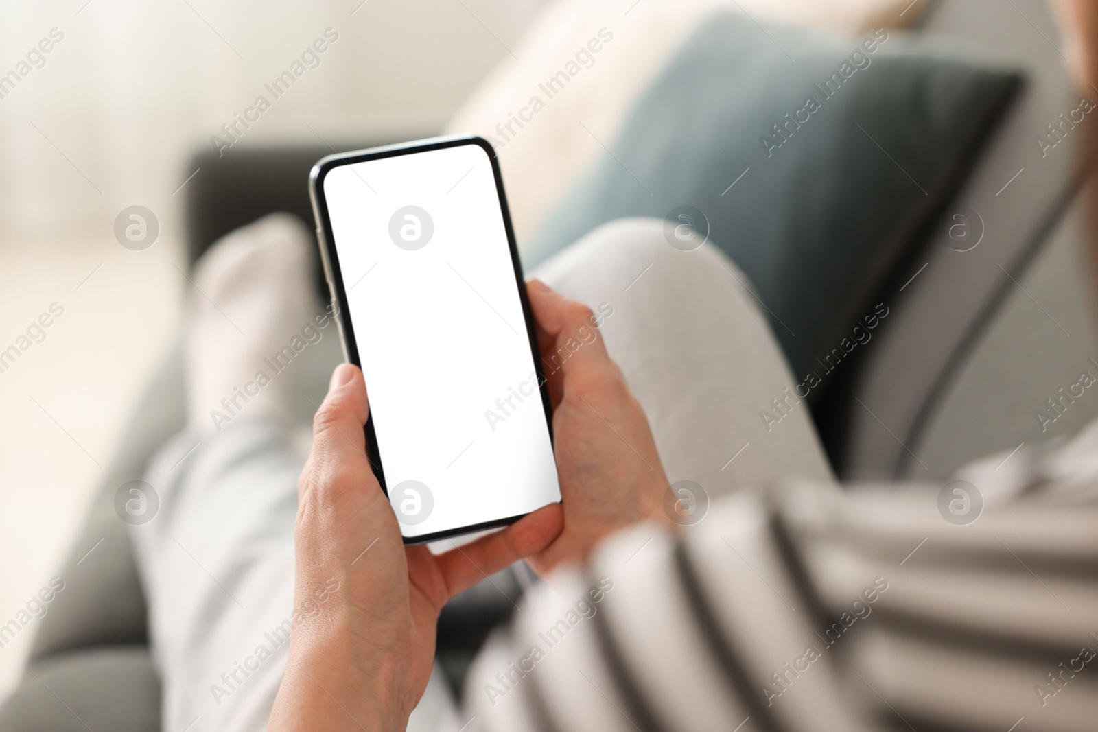 Woman using modern smartphone on sofa at home, closeup Photo of Woman using modern smartphone on sofa at home, closeup