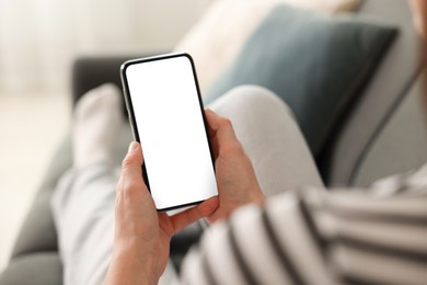 Photo of Woman using modern smartphone on sofa at home, closeup