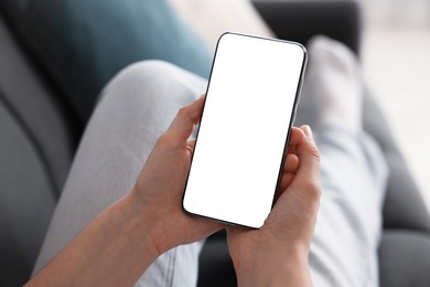 Photo of Woman using modern smartphone on sofa at home, closeup