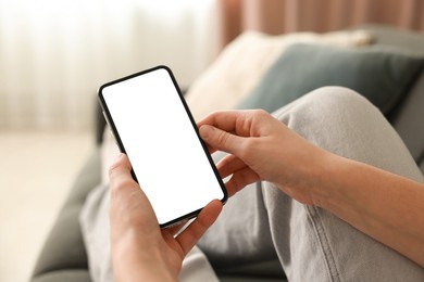 Photo of Woman using modern smartphone on sofa at home, closeup