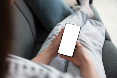 Photo of Woman using modern smartphone on sofa at home, above view