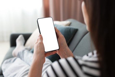 Photo of Woman using modern smartphone on sofa at home, closeup