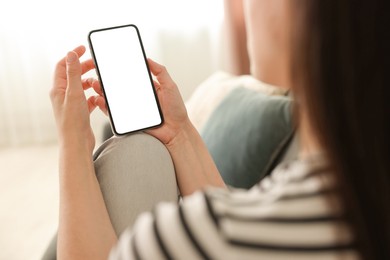 Photo of Woman using modern smartphone on sofa at home, closeup