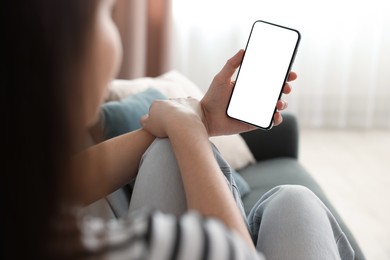 Photo of Woman using modern smartphone on sofa at home, closeup