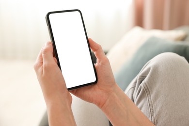 Photo of Woman using modern smartphone on sofa at home, closeup