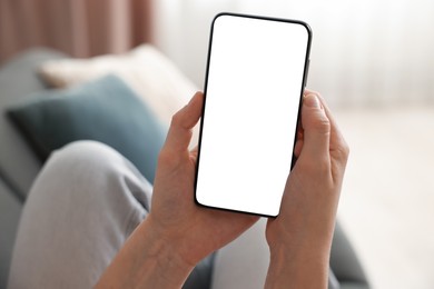 Photo of Woman using modern smartphone on sofa at home, closeup