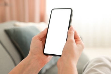 Photo of Woman using modern smartphone on sofa at home, closeup