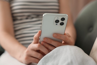 Photo of Woman using modern smartphone on sofa at home, closeup