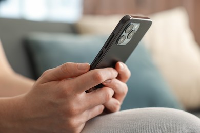 Photo of Woman using modern smartphone on sofa at home, closeup