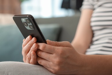 Photo of Woman using modern smartphone on sofa at home, closeup