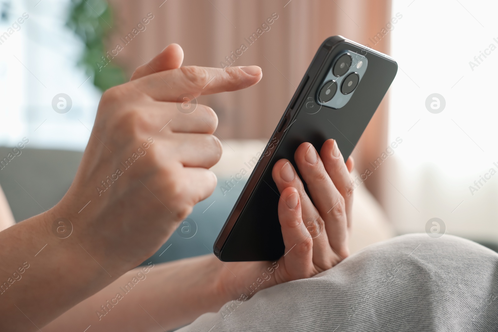 Woman using modern smartphone on sofa at home, closeup Photo of Woman using modern smartphone on sofa at home, closeup