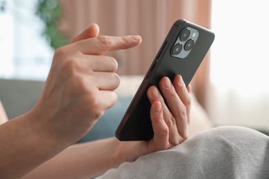 Photo of Woman using modern smartphone on sofa at home, closeup