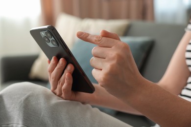 Photo of Woman using modern smartphone on sofa at home, closeup
