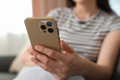 Photo of Woman using modern smartphone at home, closeup