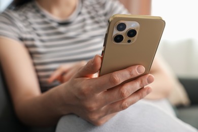 Photo of Woman using modern smartphone at home, closeup