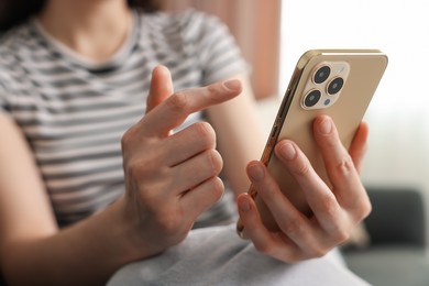 Photo of Woman using modern smartphone at home, closeup