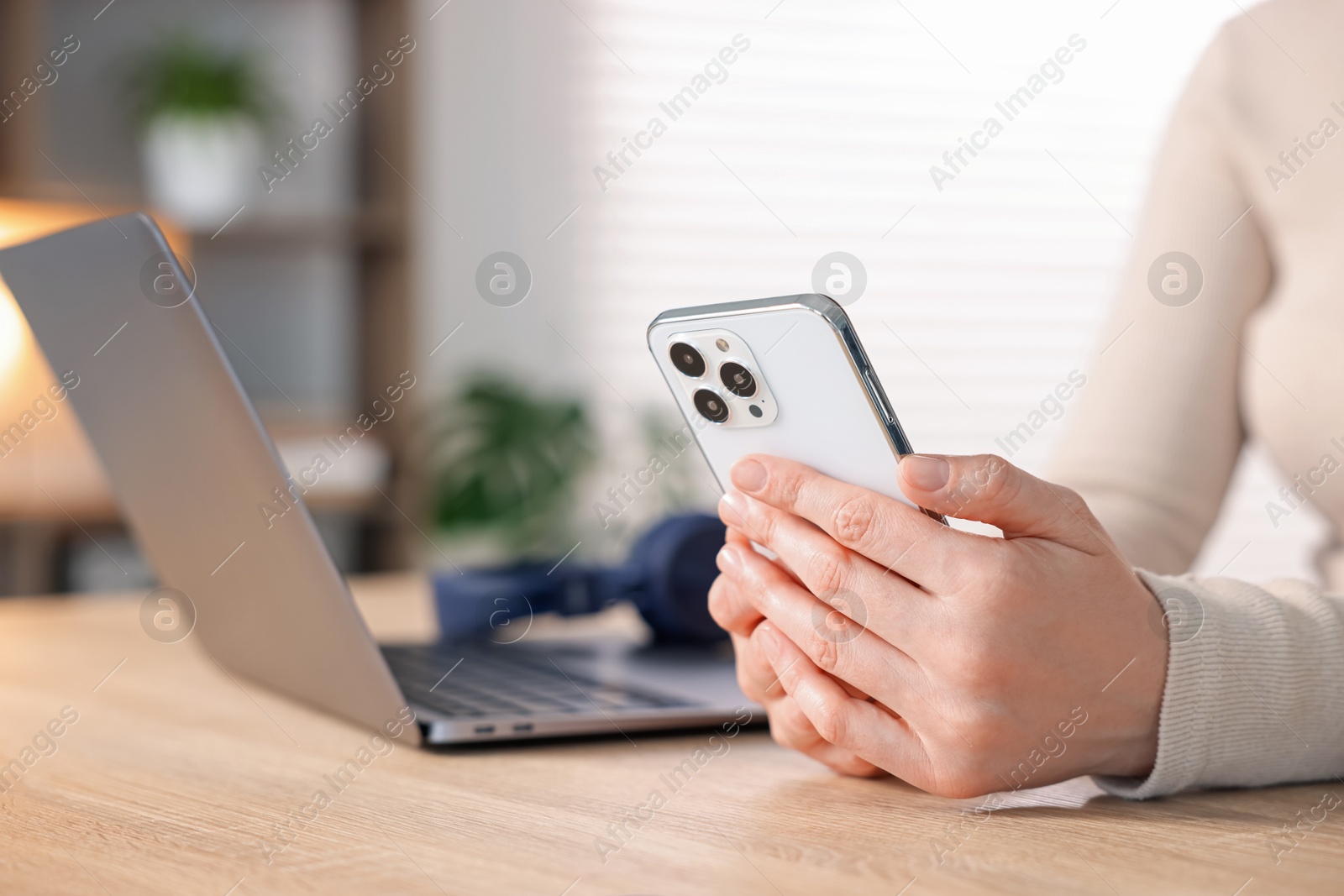 Woman using modern smartphone at wooden table indoors, closeup Photo of Woman using modern smartphone at wooden table indoors, closeup
