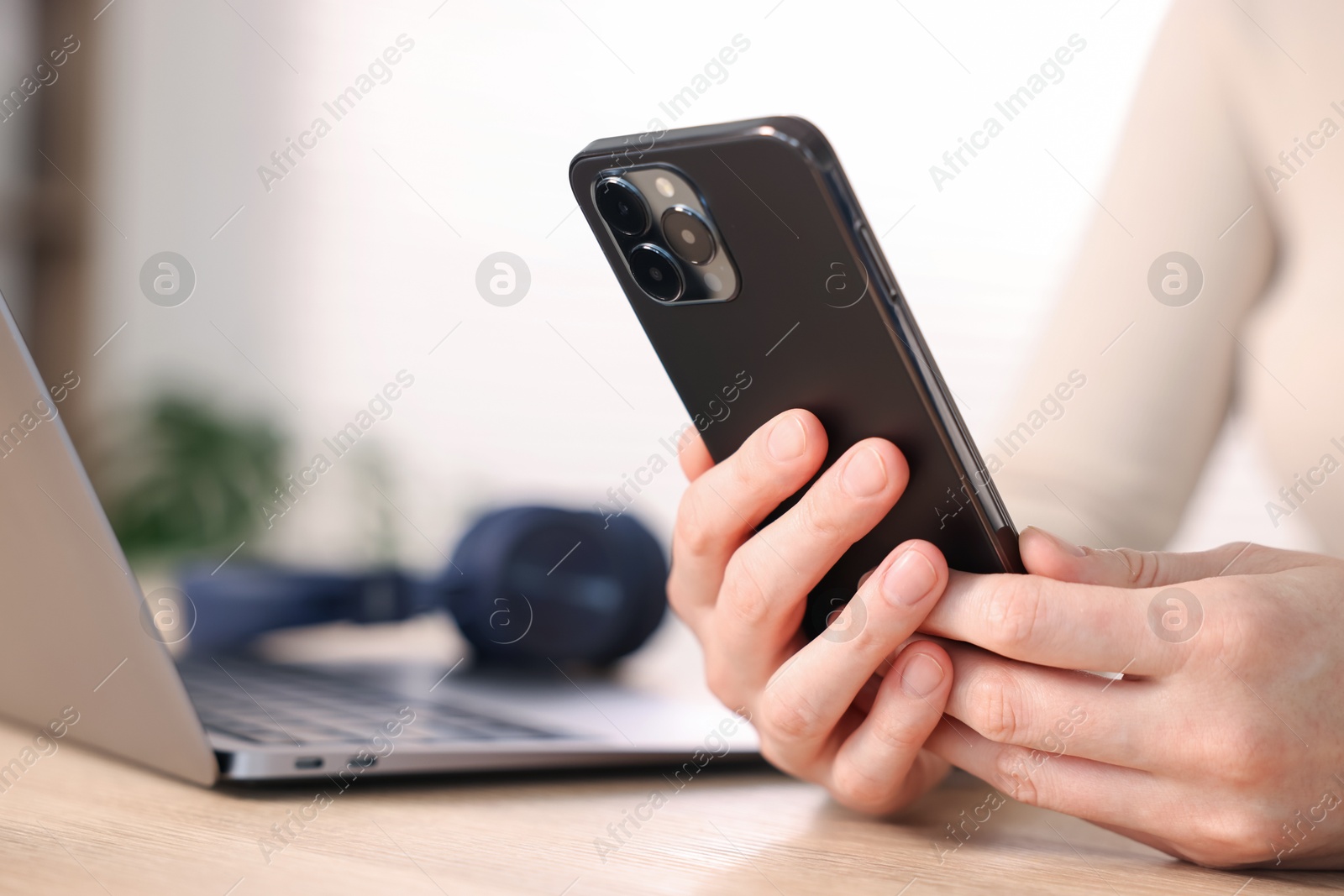Woman using modern smartphone at wooden table indoors, closeup Photo of Woman using modern smartphone at wooden table indoors, closeup
