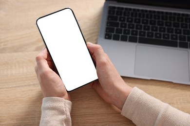 Photo of Woman using modern smartphone at wooden table, above view