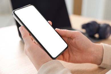 Photo of Woman using modern smartphone at table indoors, closeup