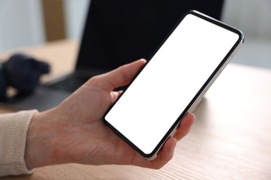 Photo of Woman using modern smartphone at table indoors, closeup
