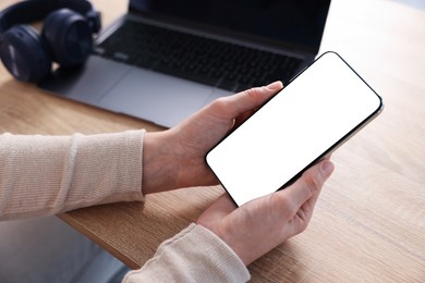 Photo of Woman using modern smartphone at wooden table, above view