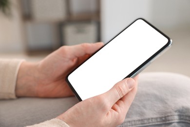 Photo of Woman using modern smartphone at home, closeup