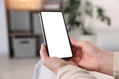 Photo of Woman using modern smartphone at home, closeup
