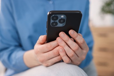 Photo of Woman using modern smartphone at home, closeup