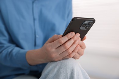 Photo of Woman using modern smartphone at home, closeup