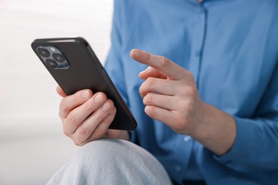 Photo of Woman using modern smartphone at home, closeup