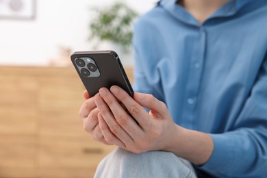 Photo of Woman using modern smartphone at home, closeup. Space for text