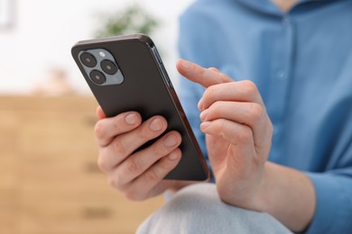 Photo of Woman using modern smartphone at home, closeup