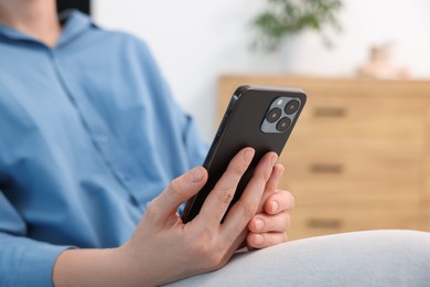 Photo of Woman using modern smartphone at home, closeup