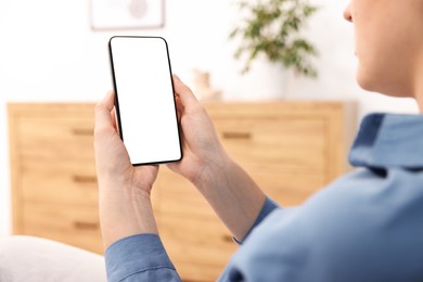 Photo of Woman using modern smartphone at home, closeup