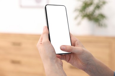 Photo of Woman using modern smartphone at home, closeup