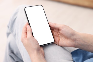 Photo of Woman using modern smartphone at home, closeup