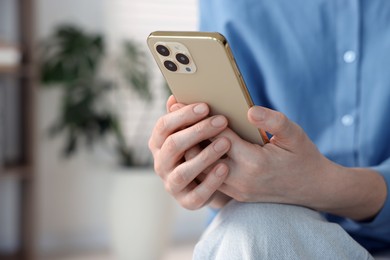 Photo of Woman using modern smartphone at home, closeup. Space for text