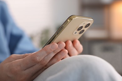 Photo of Woman using modern smartphone at home, closeup