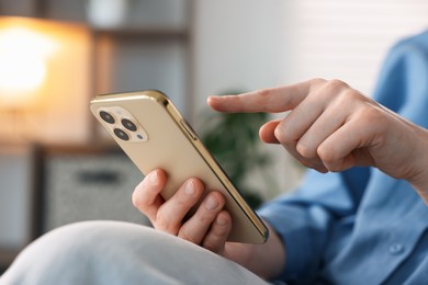 Photo of Woman using modern smartphone at home, closeup