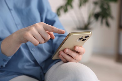 Photo of Woman using modern smartphone at home, closeup