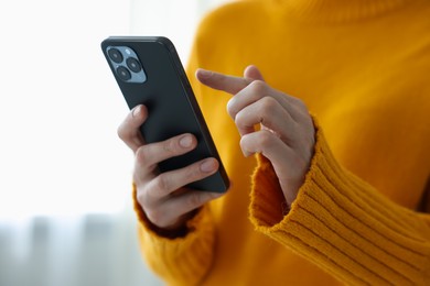 Photo of Woman using modern smartphone at home, closeup