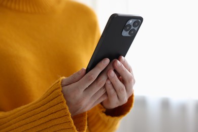 Photo of Woman using modern smartphone at home, closeup