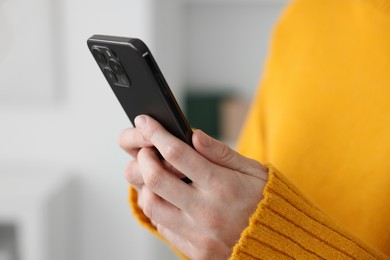 Photo of Woman using modern smartphone at home, closeup