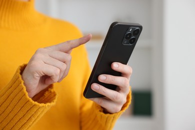 Photo of Woman using modern smartphone at home, closeup