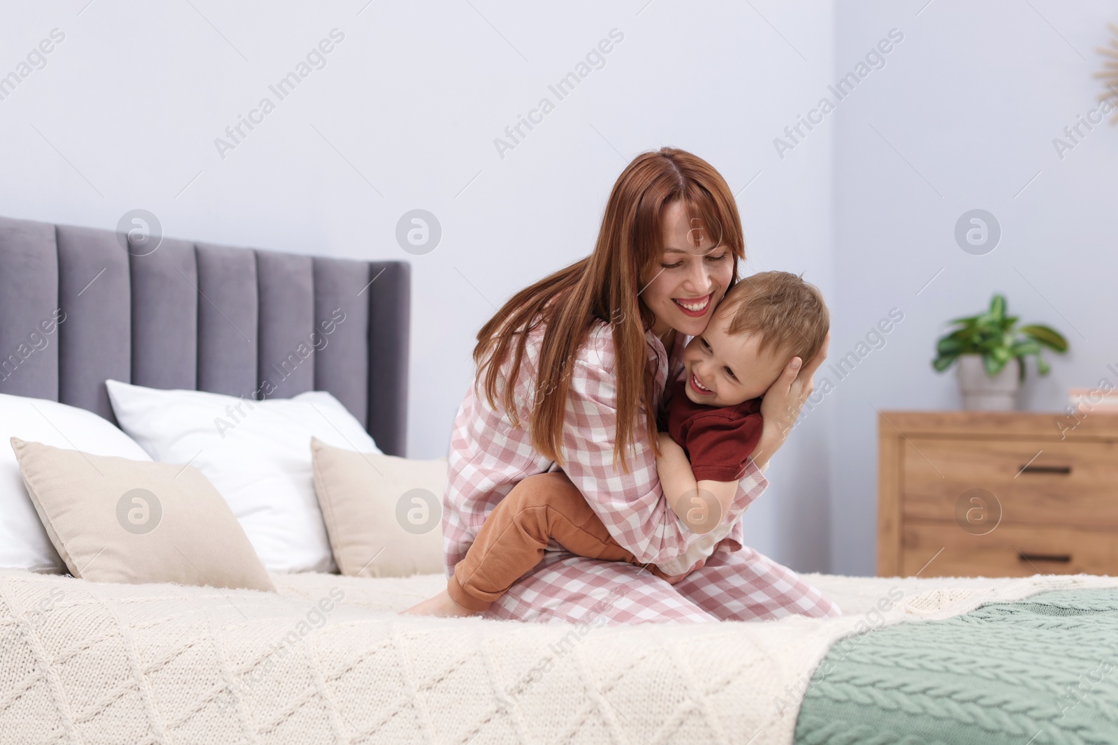 Happy mother hugging her son on bed at home Photo of Happy mother hugging her son on bed at home