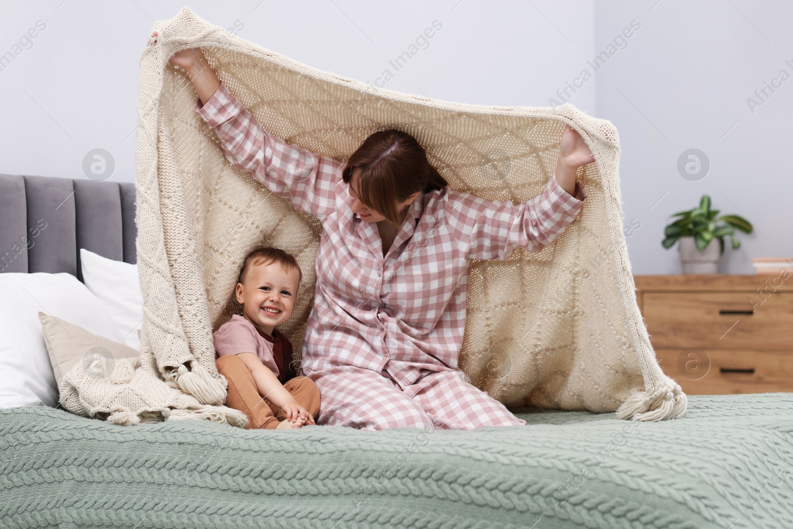 Happy mother playing with her son on bed at home Photo of Happy mother playing with her son on bed at home
