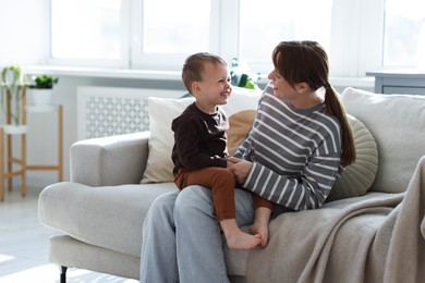 Photo of Happy mother spending time together with her son on sofa at home