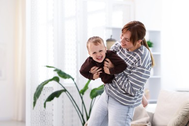 Photo of Happy mother playing with her son at home. Space for text
